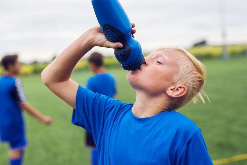 jak nawodnić organizm - chłopiec pijący wodę na meczu