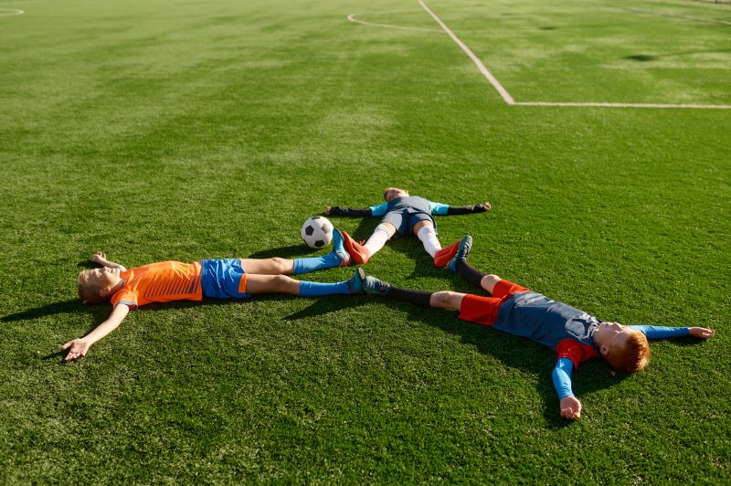 zmęczeni piłkarze leżący na murawie