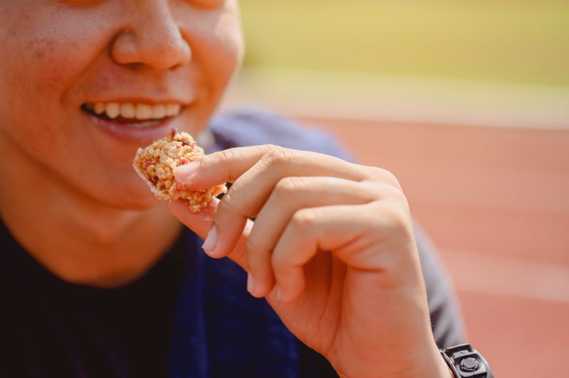 chłopiec jedzący energetyczny baton dodający sił do szybkiego biegania